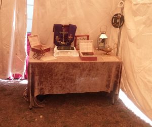 Photo of various artifacts displayed on draped tables with informational signs