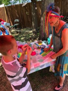 Photo of child examining a rock as older woman in colorful clothing looks on.